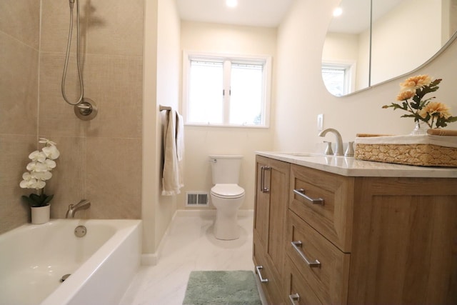 full bathroom featuring vanity, tiled shower / bath combo, and toilet