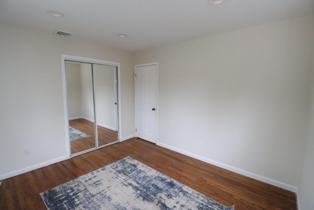 unfurnished bedroom featuring dark hardwood / wood-style floors and a closet