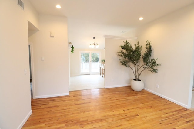 unfurnished room with an inviting chandelier and light hardwood / wood-style flooring