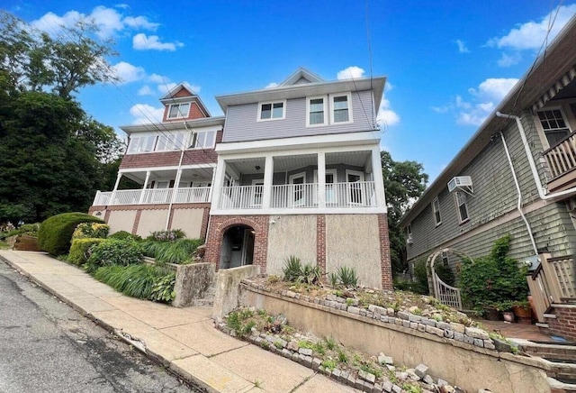 view of front of home with an AC wall unit and a balcony