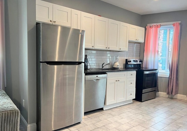 kitchen featuring tasteful backsplash, white cabinets, appliances with stainless steel finishes, and sink