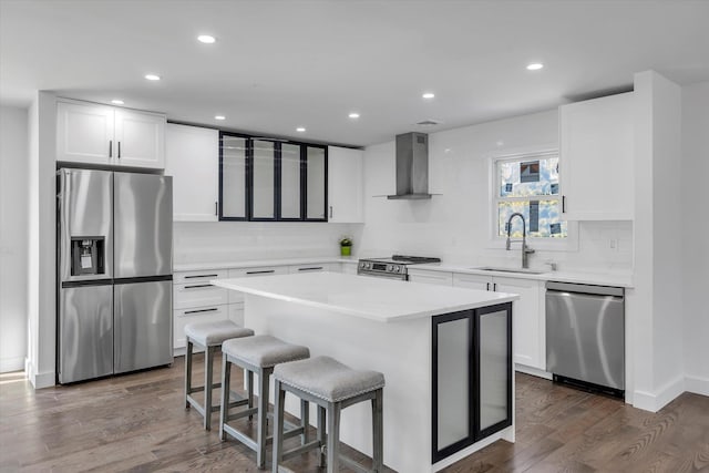 kitchen featuring sink, a center island, appliances with stainless steel finishes, dark hardwood / wood-style flooring, and wall chimney range hood