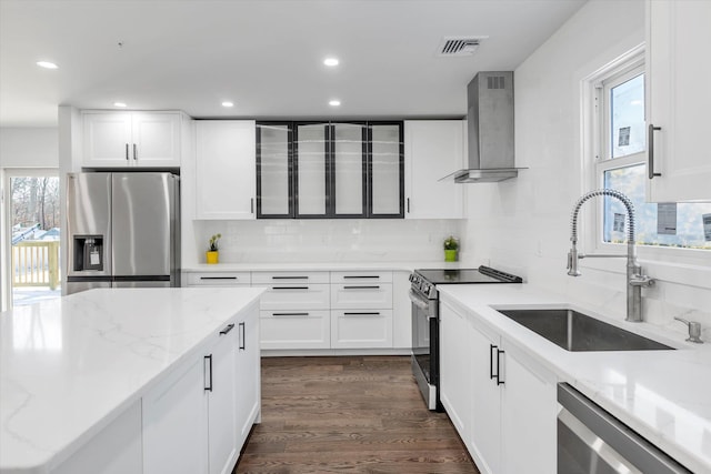 kitchen featuring white cabinets, stainless steel appliances, sink, and wall chimney range hood