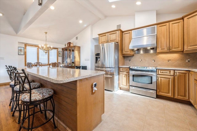 kitchen featuring wall chimney range hood, a center island, stainless steel appliances, and hanging light fixtures