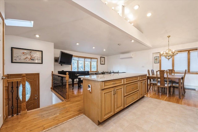 kitchen with light stone countertops, pendant lighting, a wall mounted AC, and light wood-type flooring