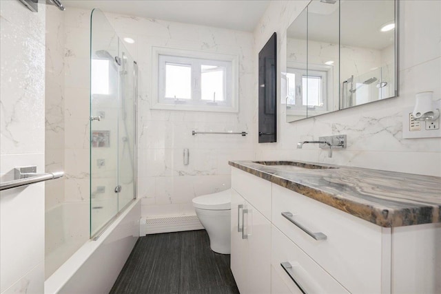 full bathroom featuring toilet, baseboard heating, tile walls, and vanity