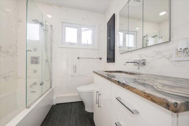 full bathroom featuring toilet, hardwood / wood-style flooring, a baseboard heating unit, tile walls, and vanity