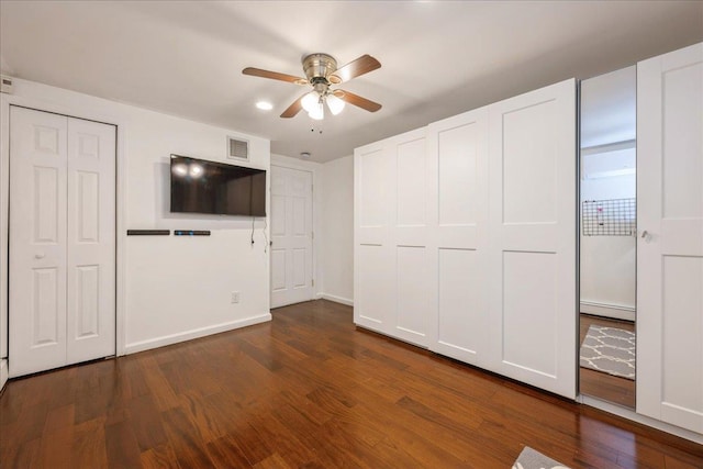 unfurnished bedroom featuring ceiling fan, baseboard heating, and dark hardwood / wood-style flooring