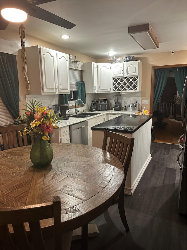 kitchen with sink, white cabinets, backsplash, stainless steel dishwasher, and dark wood-type flooring