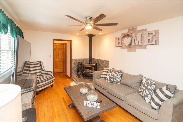 living area with a ceiling fan, light wood-type flooring, a wood stove, and recessed lighting