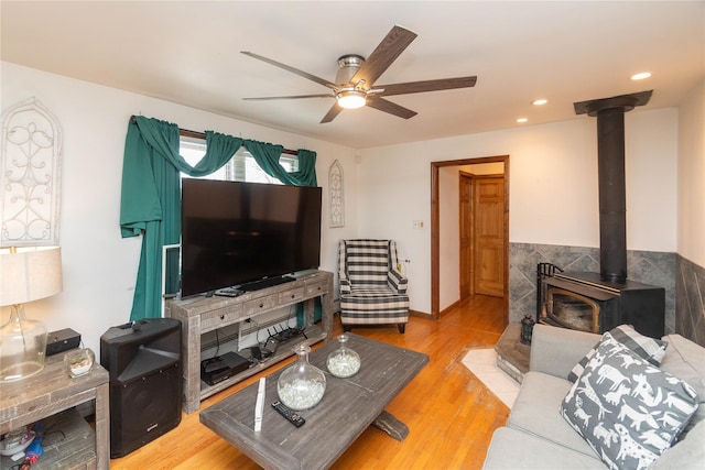 living room featuring a ceiling fan, recessed lighting, a wood stove, and light wood finished floors