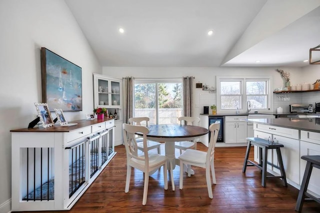 dining area featuring vaulted ceiling, dark wood-type flooring, and sink