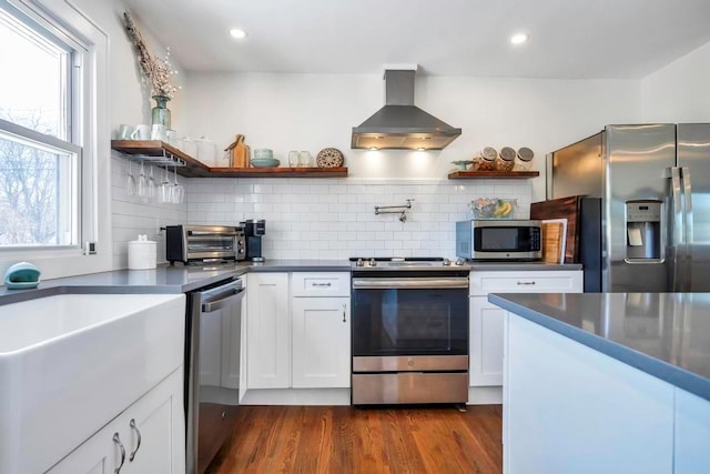 kitchen featuring appliances with stainless steel finishes, dark hardwood / wood-style floors, tasteful backsplash, white cabinets, and island exhaust hood