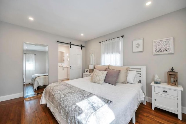 bedroom featuring dark wood-type flooring, connected bathroom, and a barn door