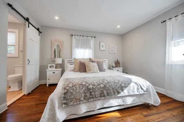 bedroom featuring dark wood-type flooring, ensuite bath, and a barn door