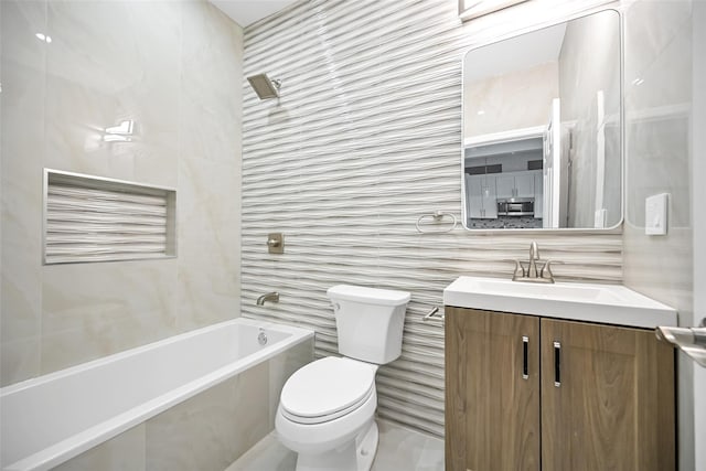 full bathroom featuring toilet, tiled shower / bath, tile walls, and vanity