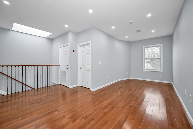 unfurnished room with a skylight and hardwood / wood-style floors