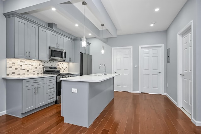 kitchen featuring an island with sink, stainless steel appliances, dark hardwood / wood-style floors, backsplash, and decorative light fixtures