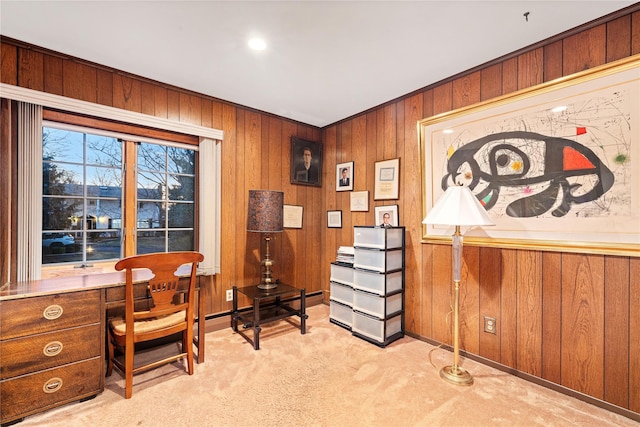 office space featuring wooden walls, light colored carpet, and built in desk