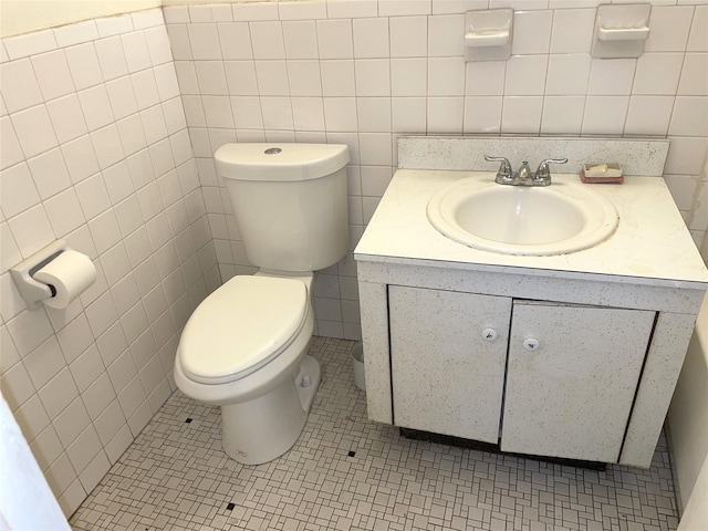 bathroom with vanity, toilet, tile walls, and tile patterned flooring