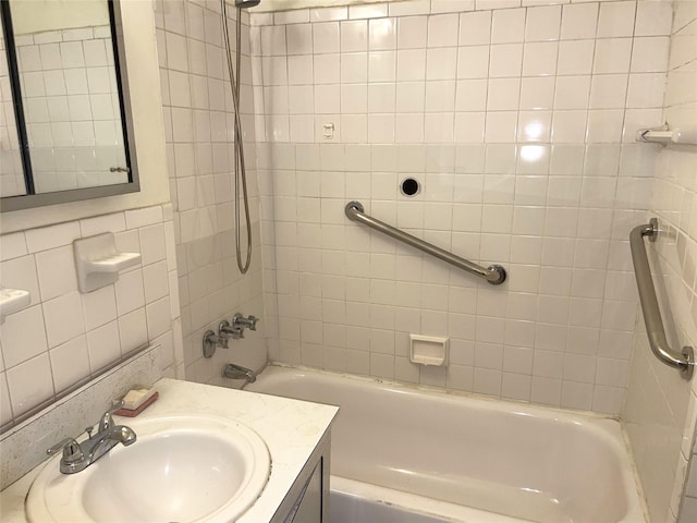 bathroom with tile walls, tiled shower / bath combo, and vanity