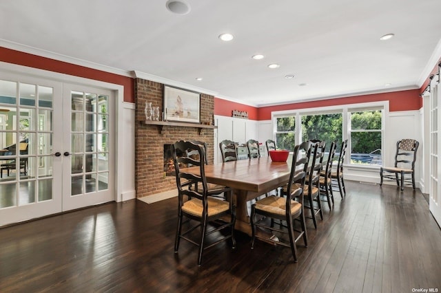 dining room featuring a brick fireplace, dark hardwood / wood-style floors, crown molding, and french doors