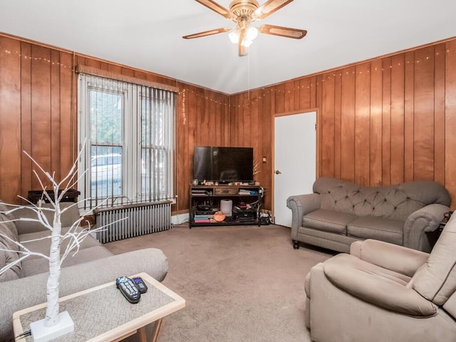 carpeted living room featuring ceiling fan and wooden walls