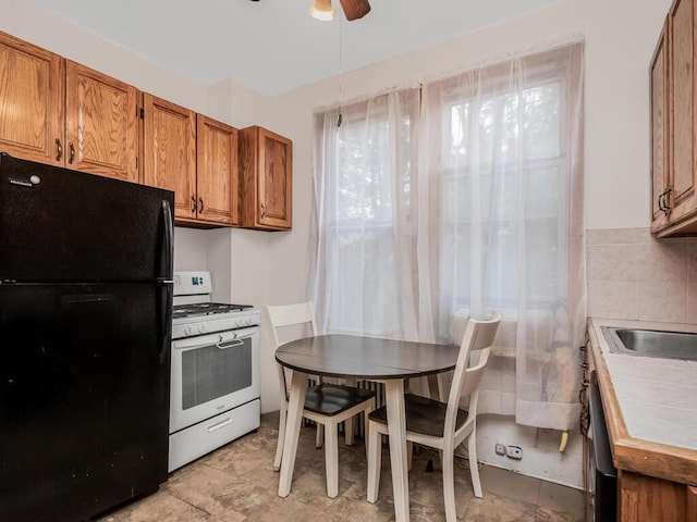 kitchen with black refrigerator, white gas range, tile countertops, and ceiling fan