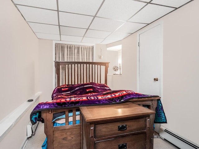 bedroom featuring a drop ceiling and a baseboard heating unit