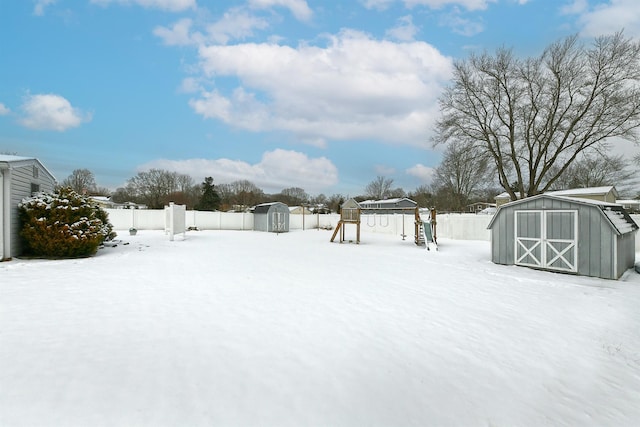 yard covered in snow with a playground and a storage unit