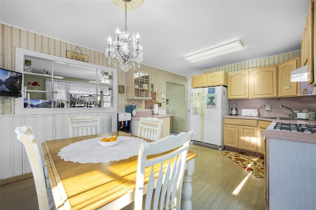 dining space featuring sink, light hardwood / wood-style flooring, and a notable chandelier