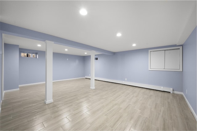 basement featuring light hardwood / wood-style floors and a baseboard heating unit