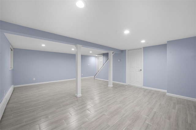 basement featuring a baseboard radiator and light hardwood / wood-style flooring