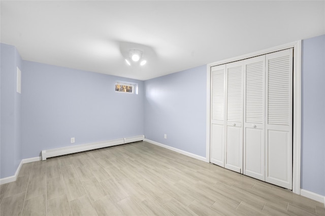 unfurnished bedroom with light hardwood / wood-style flooring, a closet, and baseboard heating