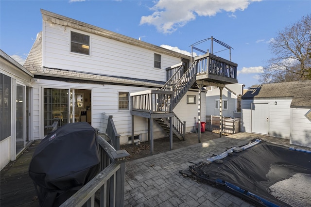 back of house with a wooden deck, a shed, and a patio