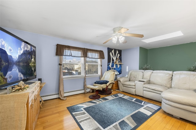 living room with baseboard heating, light hardwood / wood-style flooring, ceiling fan, and a skylight