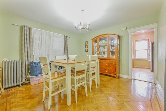 dining space with light parquet flooring, a notable chandelier, and radiator heating unit