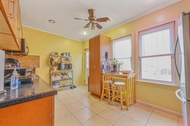 kitchen with ceiling fan, light tile patterned floors, ornamental molding, and stainless steel refrigerator