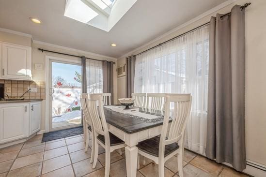 tiled dining space with crown molding, a baseboard radiator, and a skylight