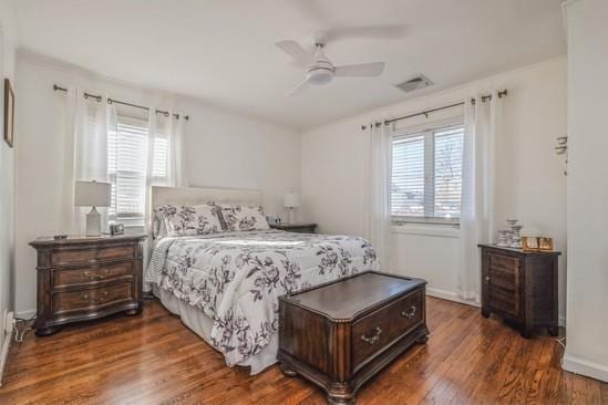 bedroom featuring ceiling fan, dark hardwood / wood-style flooring, and multiple windows