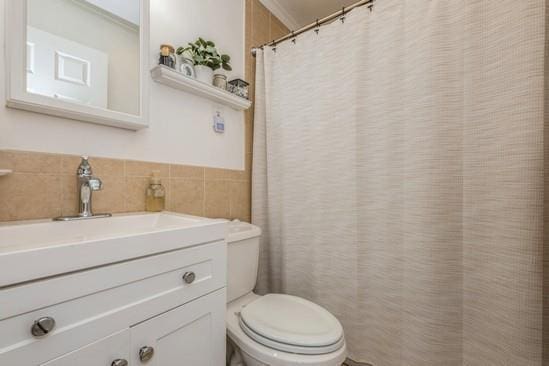 bathroom featuring ornamental molding, tile walls, vanity, and toilet