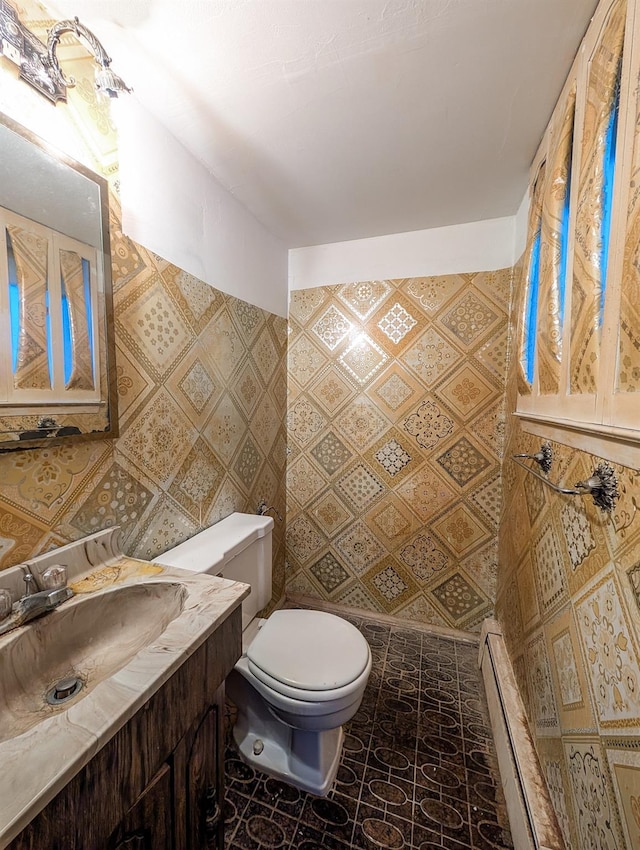 bathroom featuring toilet, a baseboard heating unit, and vanity