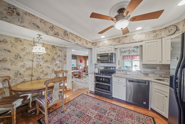 kitchen with light stone countertops, backsplash, white cabinetry, and stainless steel appliances