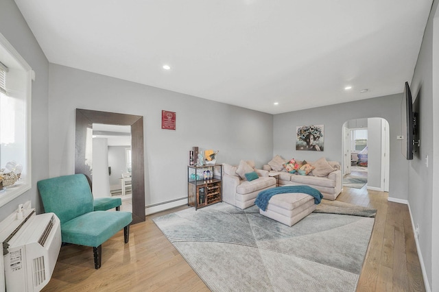 living room with a baseboard heating unit and light wood-type flooring