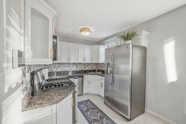 kitchen with sink, appliances with stainless steel finishes, dark stone counters, and white cabinetry