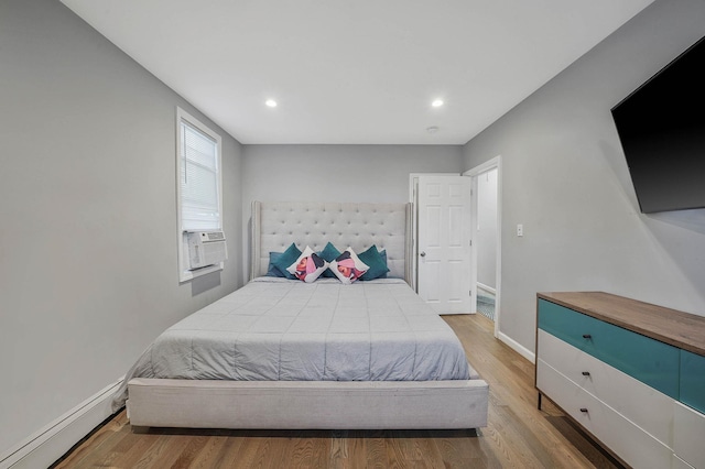 bedroom with light wood-type flooring, baseboard heating, and cooling unit