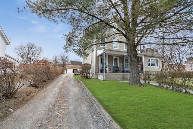 view of front of home featuring covered porch, a front yard, and a garage