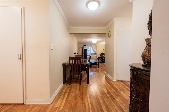 corridor with light hardwood / wood-style floors and ornamental molding