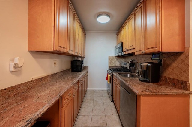 kitchen with light stone countertops, appliances with stainless steel finishes, sink, and tasteful backsplash