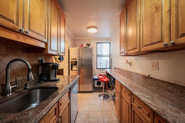 kitchen with appliances with stainless steel finishes, light tile patterned flooring, stone countertops, crown molding, and sink